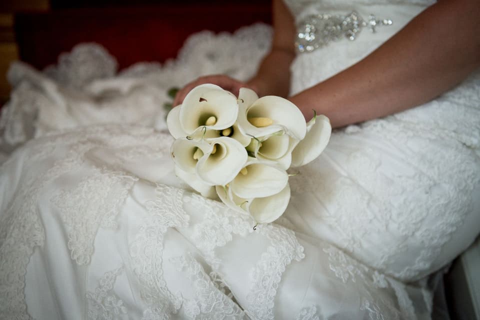 Eine Braut hält einen Strauß Calla-Lilien in der Hand.
