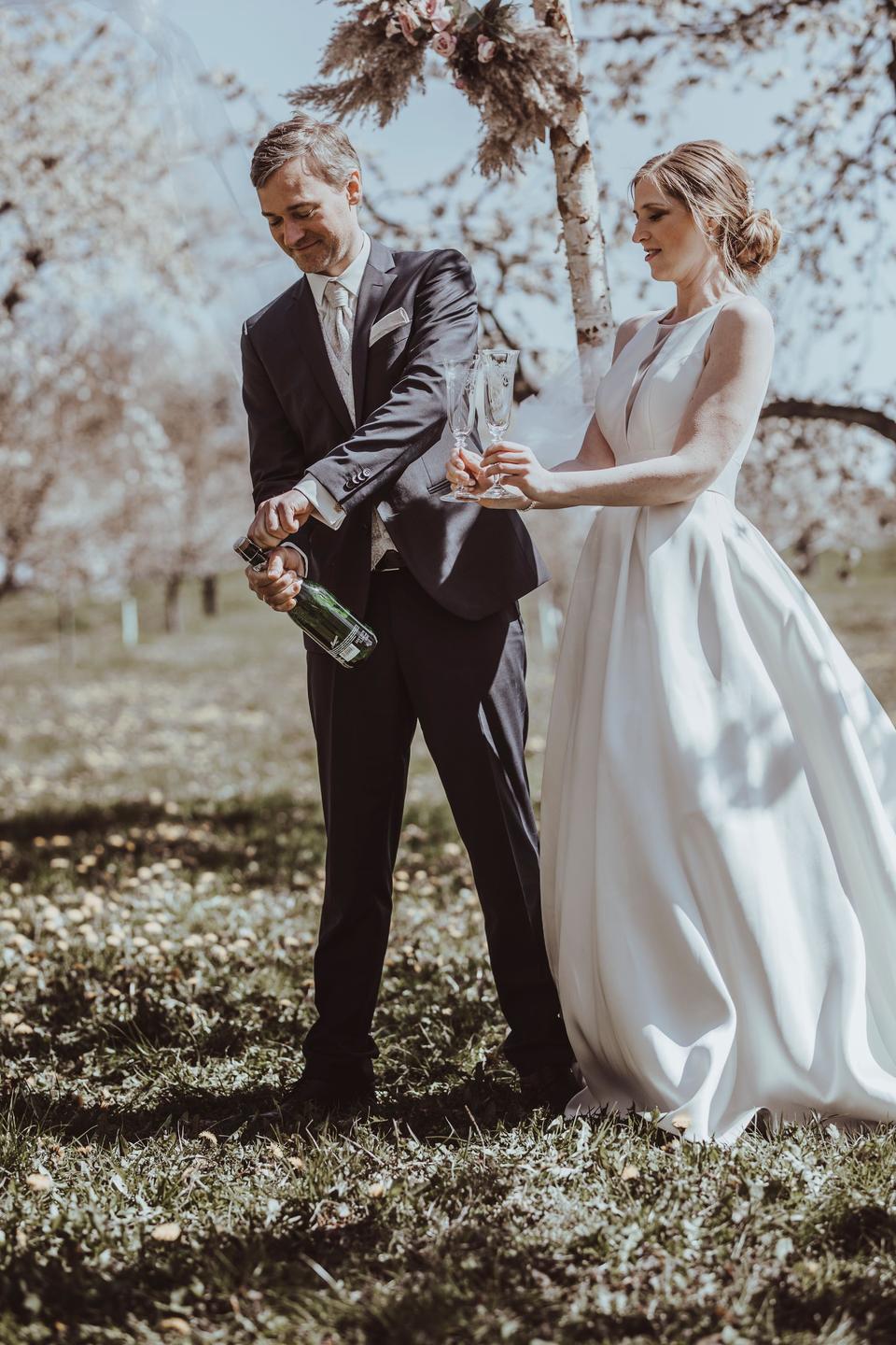 Brautpaar öffnet Champagner und stoßt an