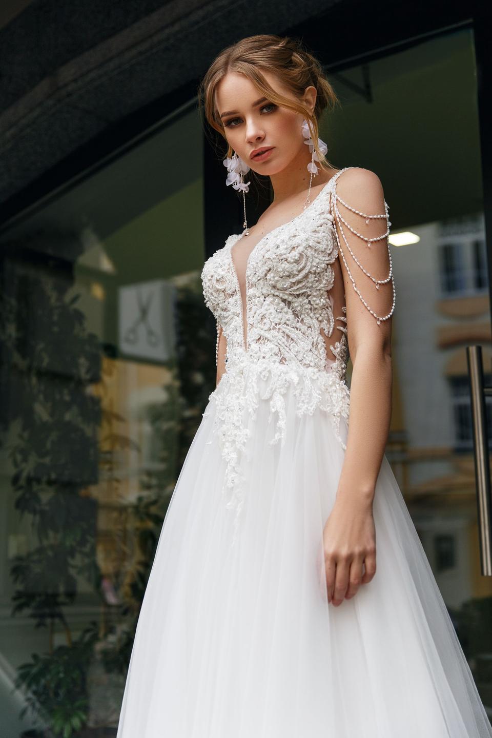 Frau in weissem Brautkleid mit Perlenelementen am Arm