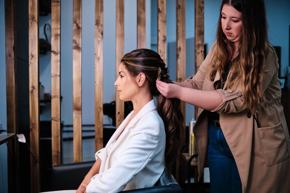 Brautstylistin frisiert die Braut