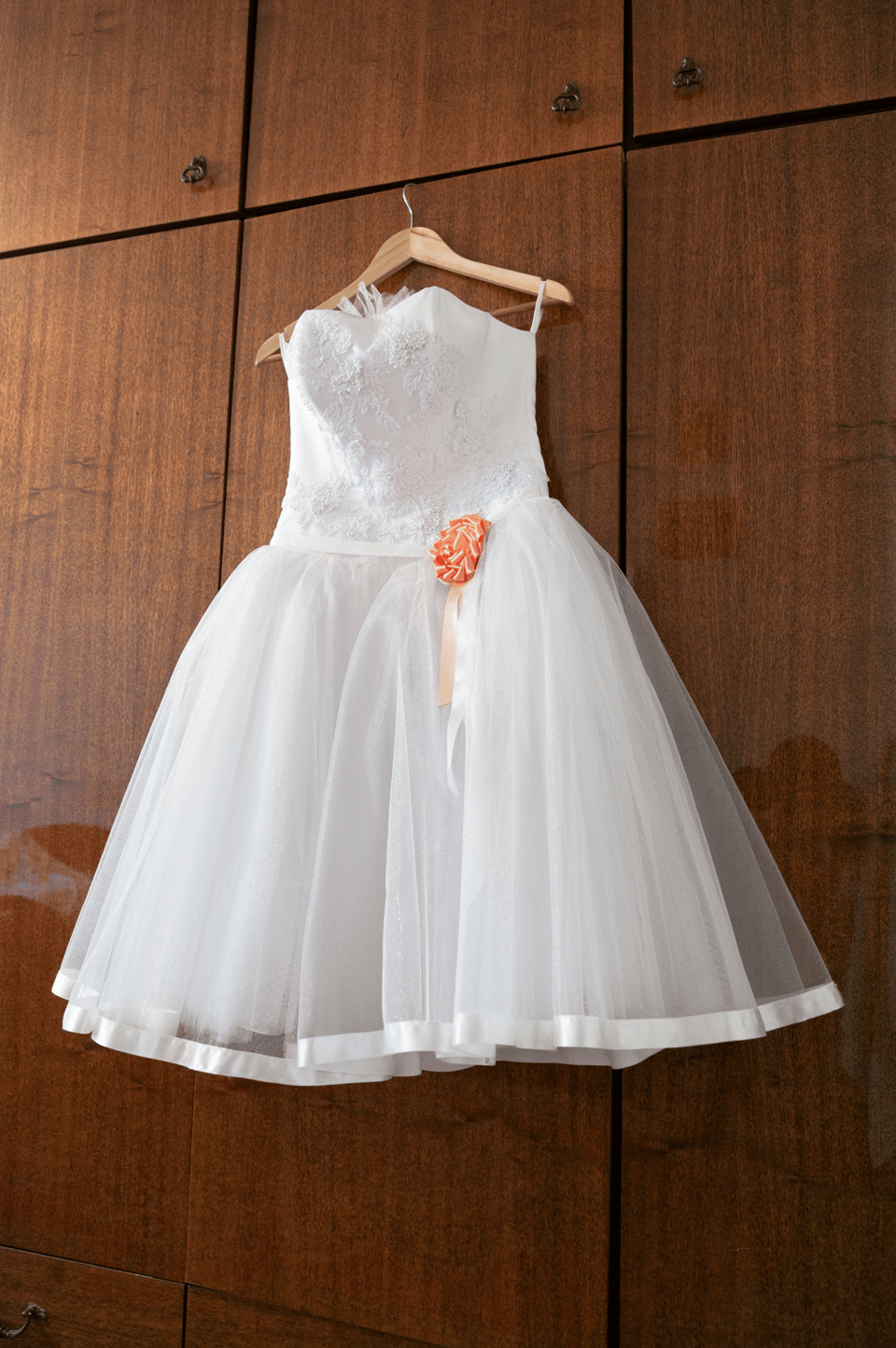Ein kurzes Brautkleid hängt am Schrank