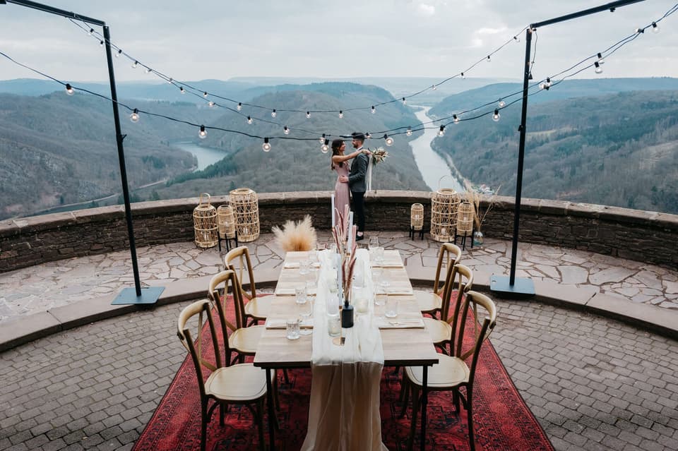 Brautpaar steht hinter dem Tisch mit Ausblick