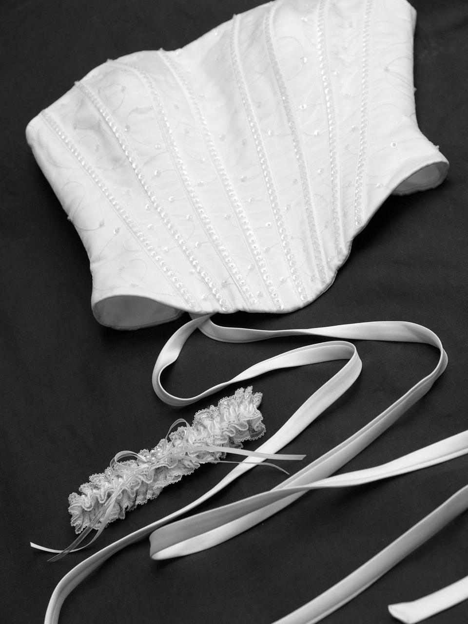 Eine weiße Corsage liegt auf schwarzem Untergrund