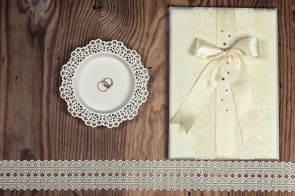 Hochzeitseinladung: Eine Einladung liegt mit Spitze auf einem Tisch