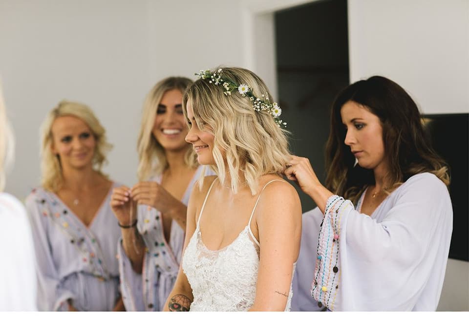 Getting Ready: Braut mit ihren Freundinnen vor der Trauung. Haarkranz Blumen wird gebunden