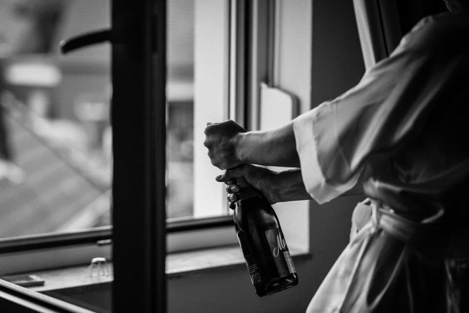 Die Braut öffnet eine Flasche Sekt.