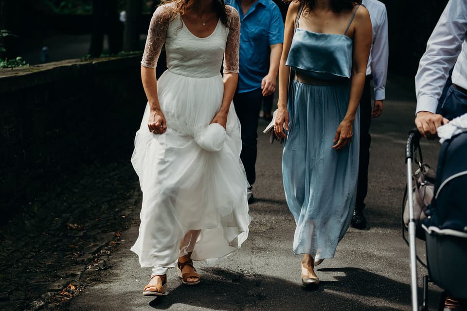 Die Braut hebt ihr Kleid hoch und läuft mit Sandalen