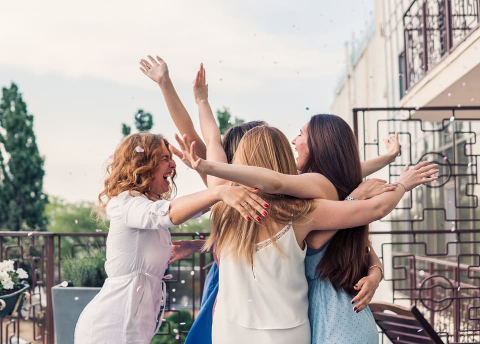 Freundinnen umarmen sich lachend bei der Bachelorette Party