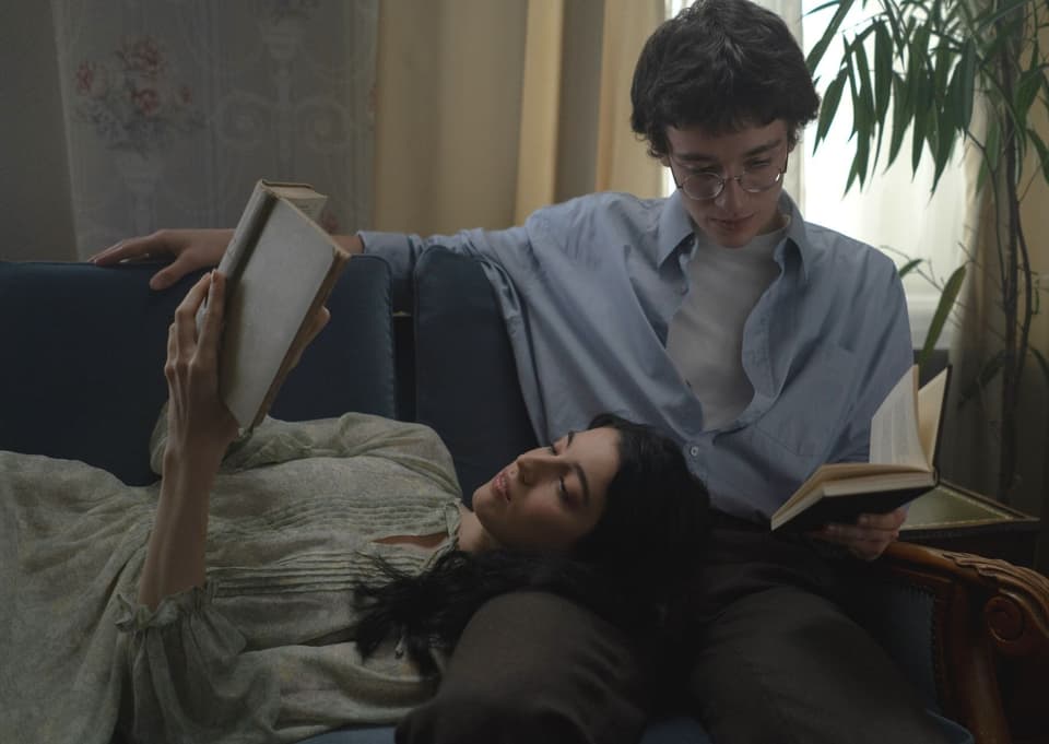 Paar sitzt bzw. liegt auf dem Sofa und hält jeweils ein Buch in der Hand