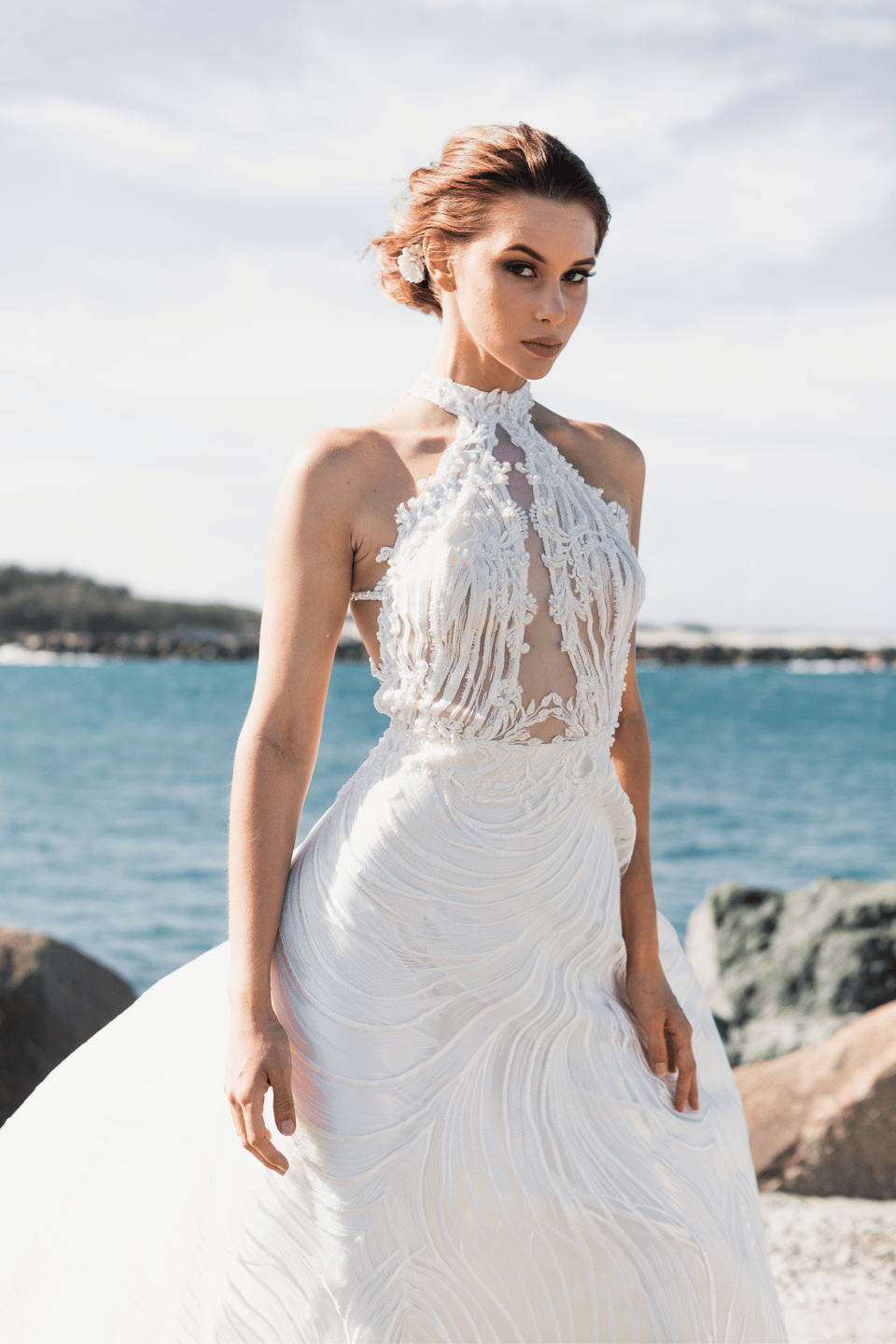 Die Braut trägt ein Neckholder Brautkleid und dazu eine Hochsteckfrisur.