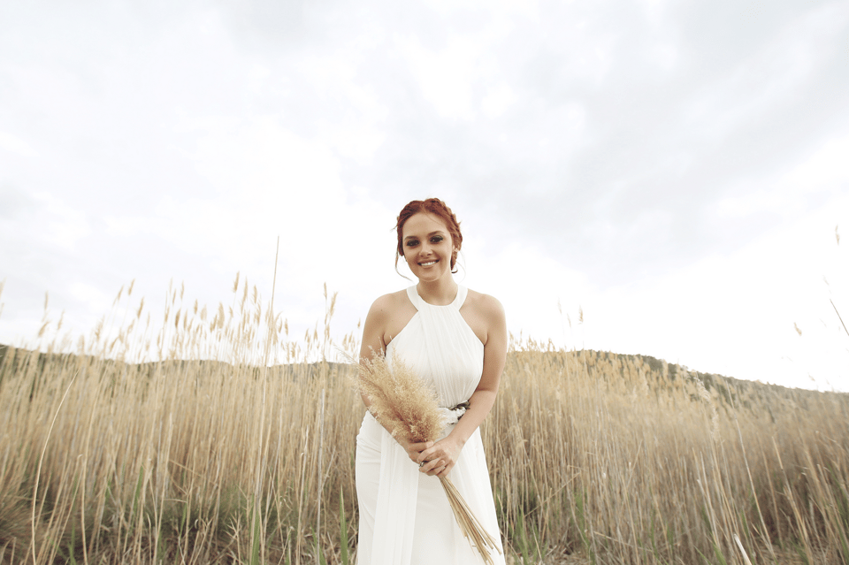 Die Braut trägt ein Neckholder Brautkleid und dazu eine Hochsteckfrisur.