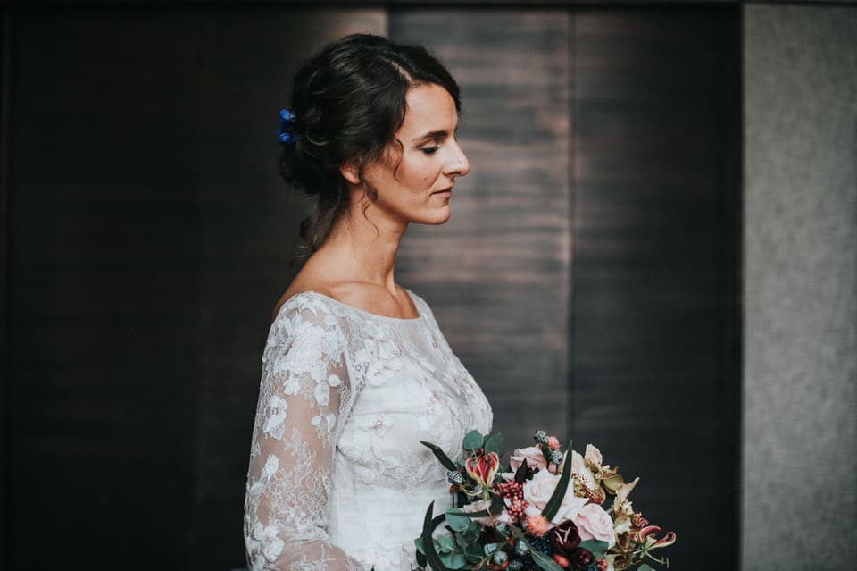 Die Braut trägt ein Brautkleid mit langen Ärmeln und dazu eine gesteckte Nackenvariation.