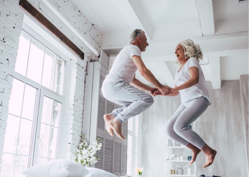 Senior Paar hüpft auf dem Bett