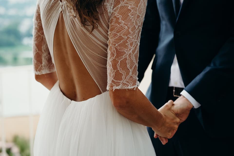 Der Bräutigam trägt ein klassischen schwarzen Anzug und die Braut ein weißes Hochzeitskleid.