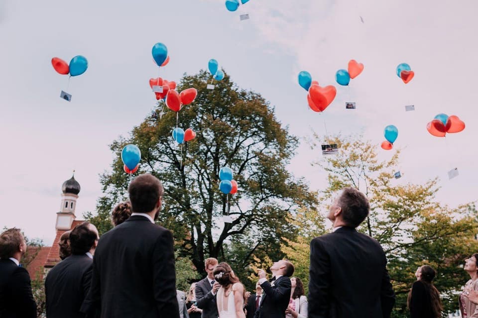 Gäste, die zu roten und blauen Luftballons hinaufschauen