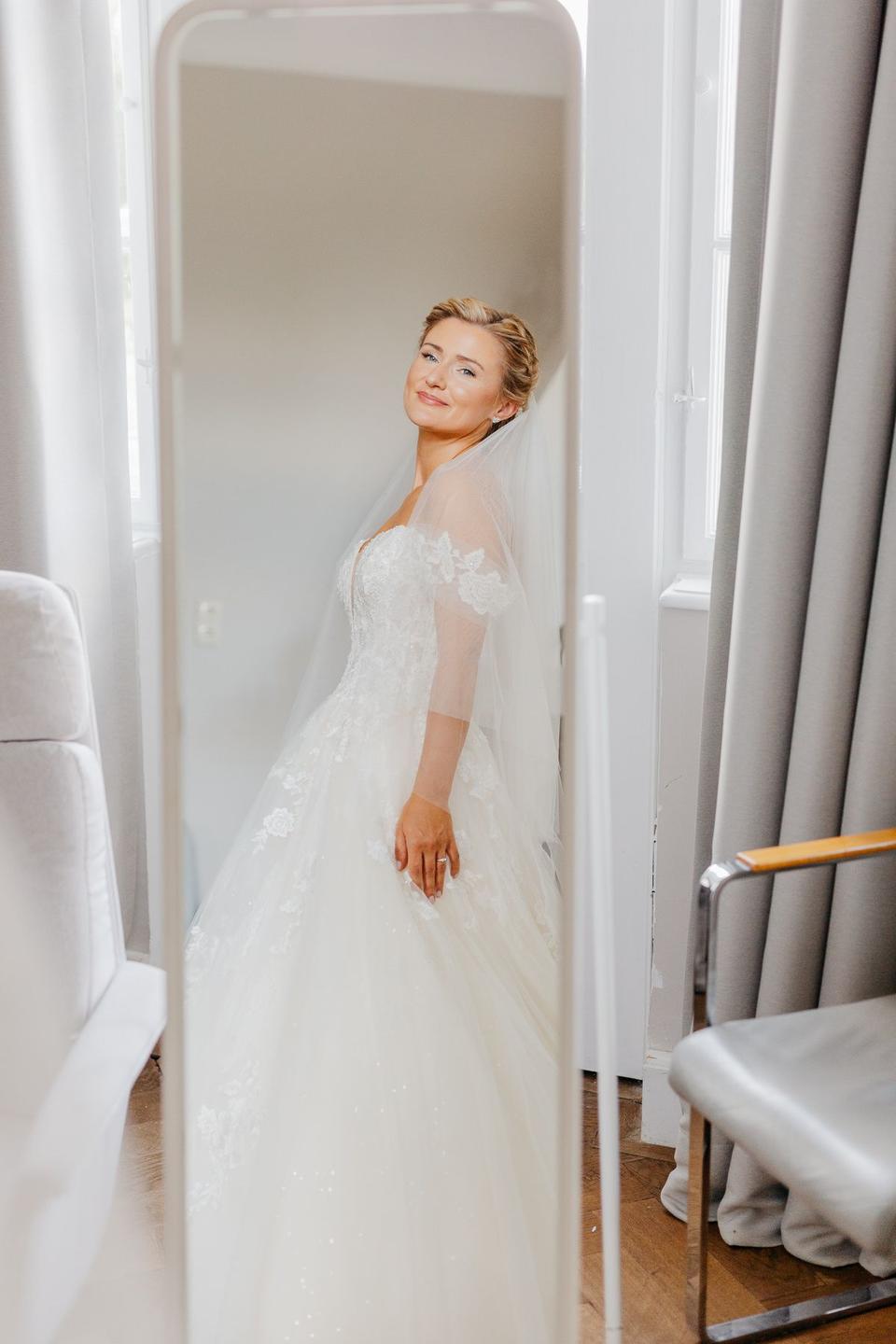 Die Braut trägt ein weißes Hochzeitskleid.