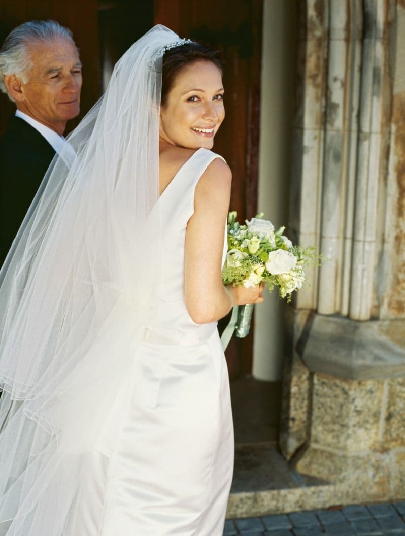 Der Weg zur kirchlichen Trauung: Braut wird auf ihrer Hochzeit vom Vater zum Altar geführt