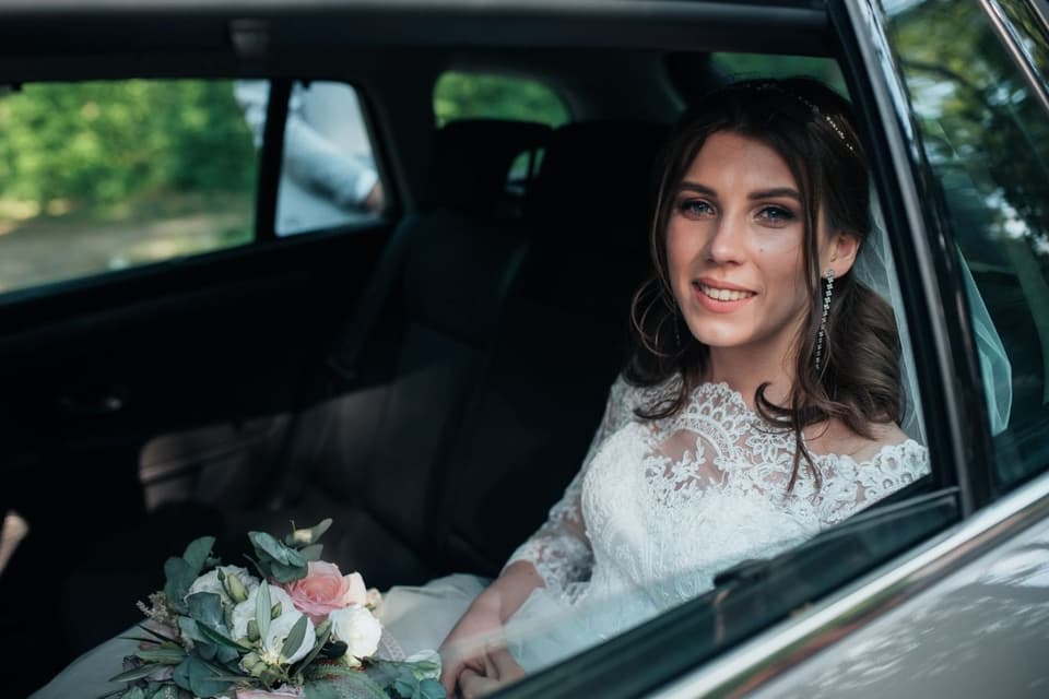 Braut sitzt nervös im Hochzeitsauto auf dem Weg zu ihrer Trauung