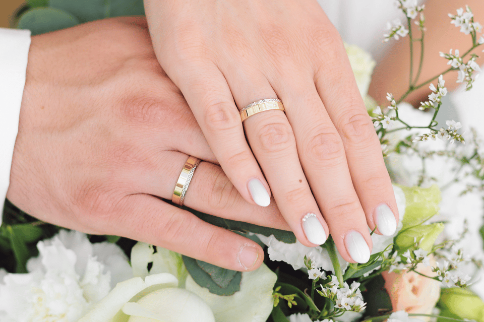 Die Braut hat Glitzersteine auf dem Nagel ihres Ringfingers.