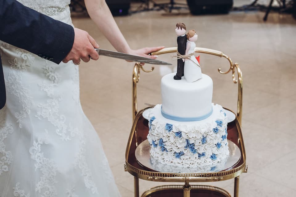 Brautpaar schneidet Hochzeitstorte mit Tortenfigur an