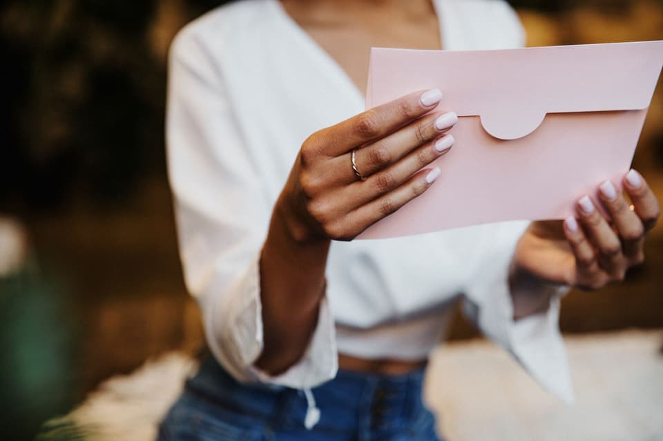 Postkartenspiel: Frau hält Postkarte im DIN A6 Format