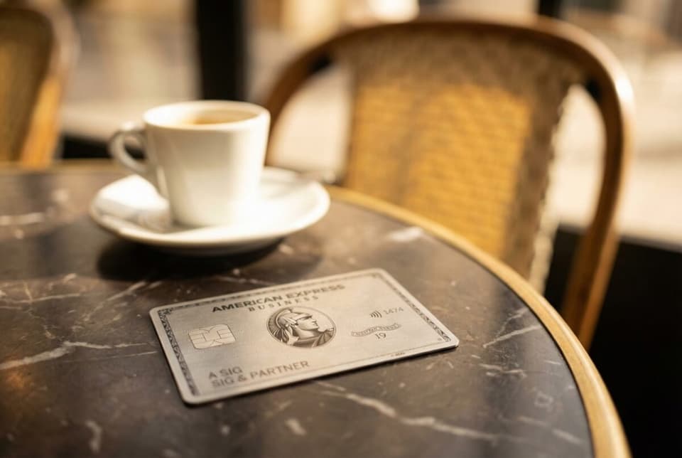 Schräg platzierte American Express Business Platinum Karte auf einem Pariser Bistro-Tisch, warme Tageslichtstimmung mit weichem Bokeh.