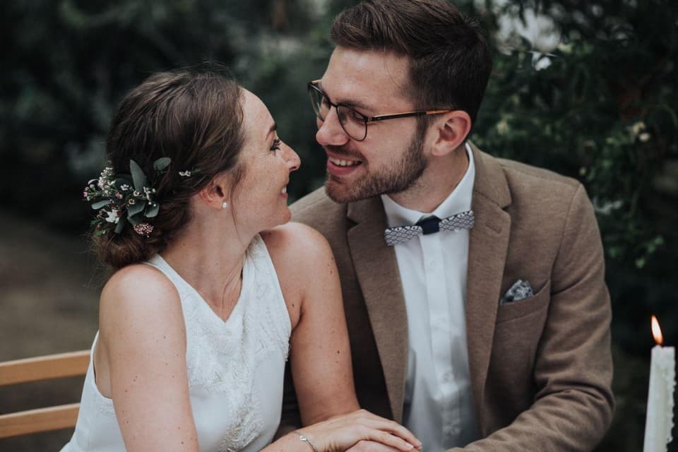 Braut mit floralem Haarschmuck und Bräutigam mit Holzfliege