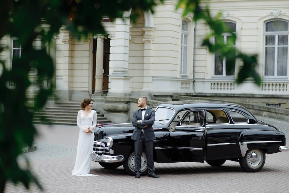 Brautpaar mit ihrem Hochzeitsauto