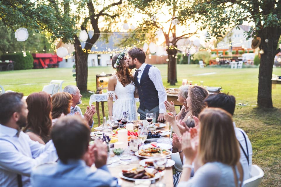 Hochzeitspaar küsst sich auf der Gartenhochzeit vor den Gästen