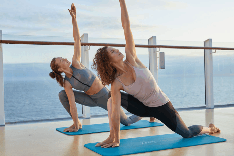 Zwei Personen führen synchron eine Yoga-Pose im Freien aus.