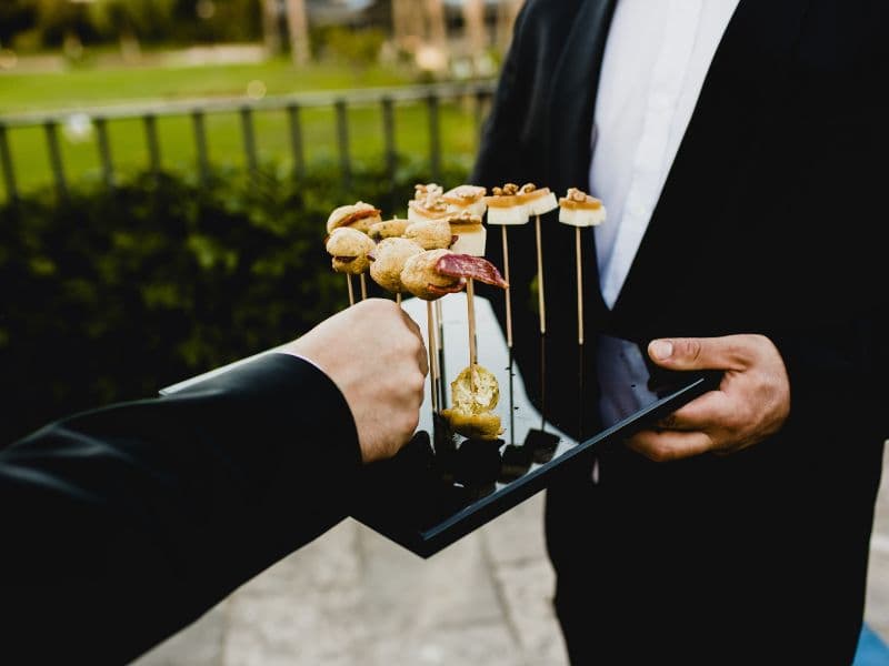 Ein Mann hält ein Tablett mit Essen am Spieß in der Hand.