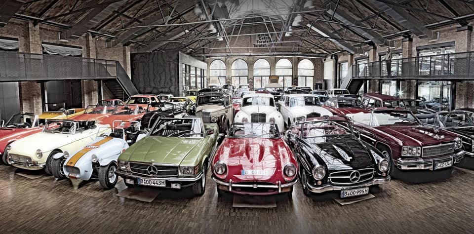 Viele Oldtimer parken in einem großen Gebäude.