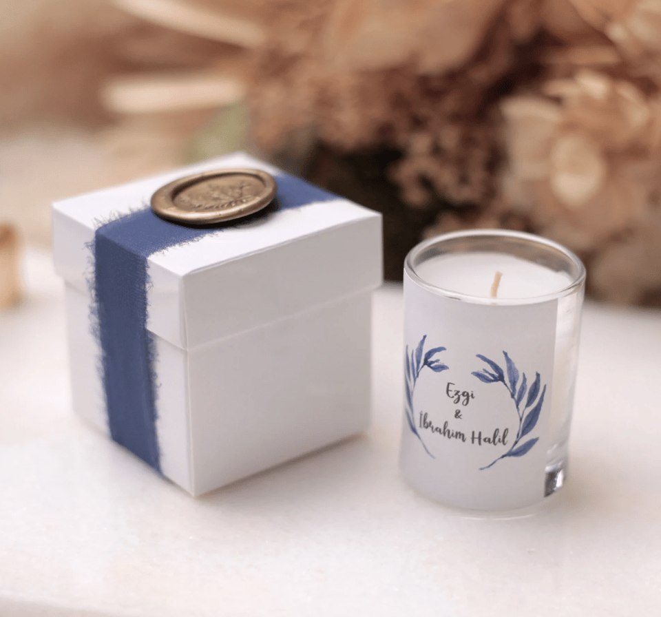 Eine Kerze mit blauem Band und einer Geschenkbox.