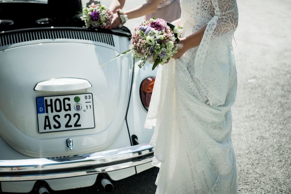 Braut steht in Kleid vor Käfer
