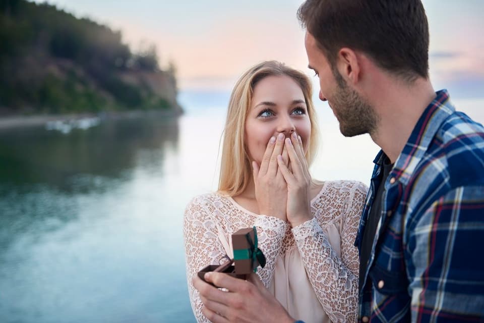 Mann macht Frau einen Heiratsantrag am Wasser