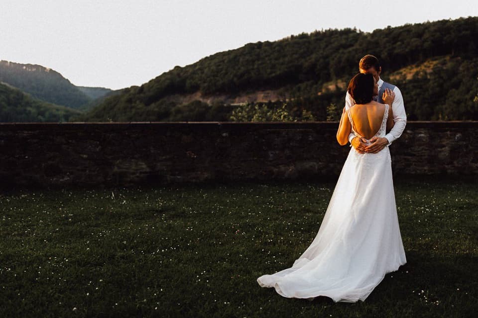 Hochzeitspaar küsst sich im Sonnenuntergang vor bergiger Kulisse
