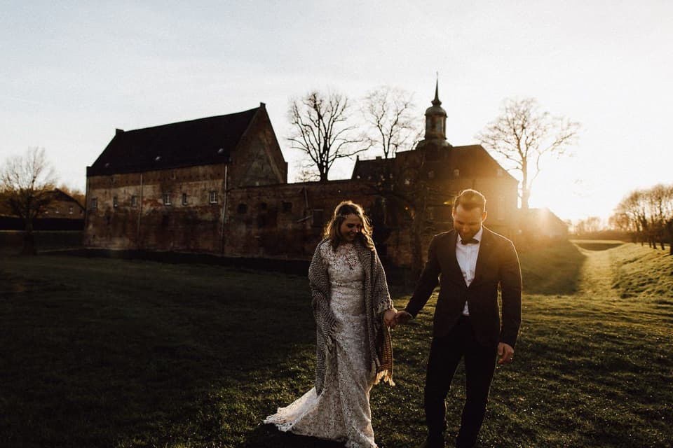 Hochzeitspaar im Sonnenuntergang vor einer Burg