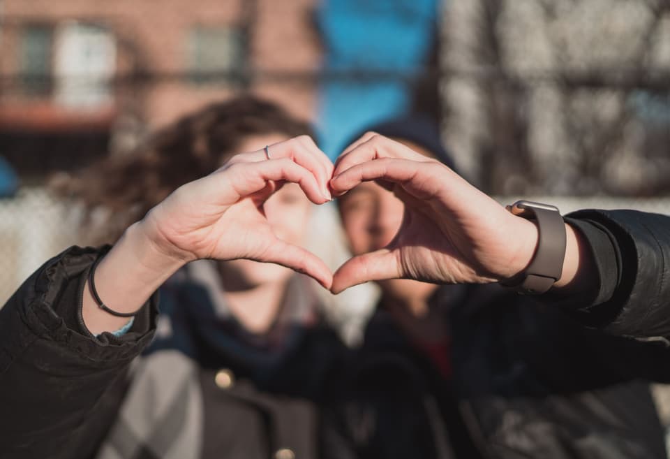 zwei Menschen formen Herz mit Hand