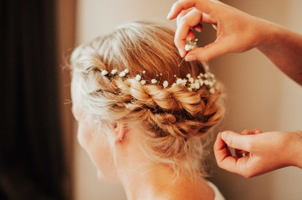 Der Braut wird eine Haarnadel in die aufwendige Frisur gesteckt.