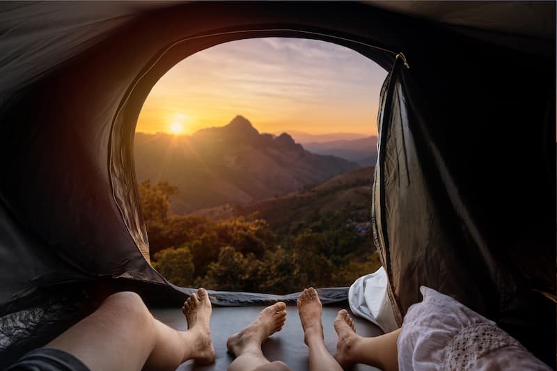 Junges Paar wacht zum Sonnenaufgang im Baumzelt auf